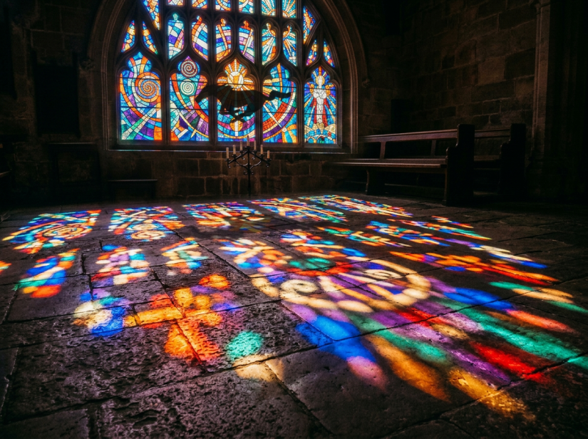 Colorful stained glass light patterns on stone floor of church interior